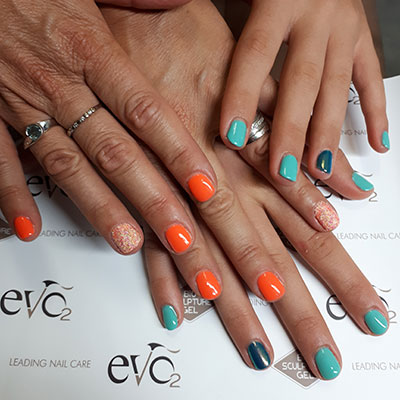 Paires de mains avec ongles orange et pailleté blanc orange, et turquoise et vert